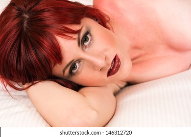 Pretty petite redhead lying nude in bed