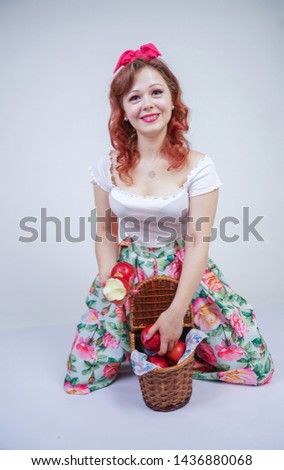 pretty pin up caucasian young girl happy posing with red apples. cute vintage lady in retro dress having fun with fruits on white background alone. vegetarian funny female loves good food and vitamins