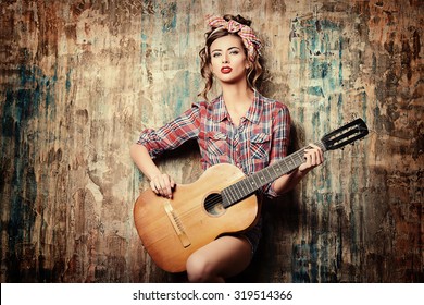 Pretty pin-up girl posing with guitar. Beauty, fashion.