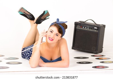 Pretty Pinup Girl Talking On Telephone Lying On The Floor With Vynil Records And A Speaker Isolated On White