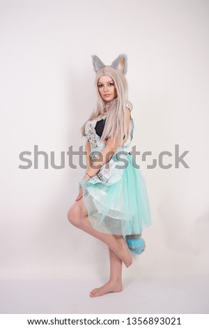pretty playful young girl with cat ears and long fluffy fur tail wearing kitchen apron on white background isolated