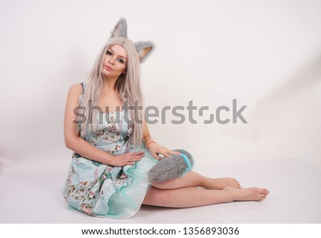 pretty playful young girl with cat ears and long fluffy fur tail wearing kitchen apron on white background isolated