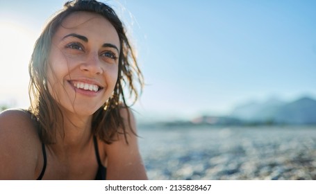 Pretty positive woman at beach. Close up face of beautiful smiling girl with sunlight at seashore