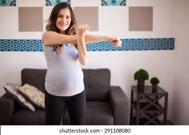 Pretty Pregnant Brunette Warming Up And Doing Some Stretching Exercises At Home