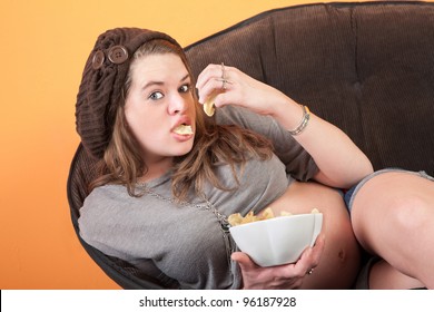 Pretty Pregnant Woman Resting On Couch Eats Potato Chips