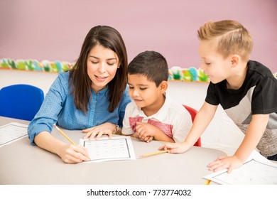 Pretty Preschool Teacher Helping Students With Some Math Exercises In The Classroom