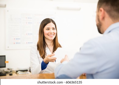 Pretty Receptionist Handing Over Lab Test Results To A Patient With A Smile