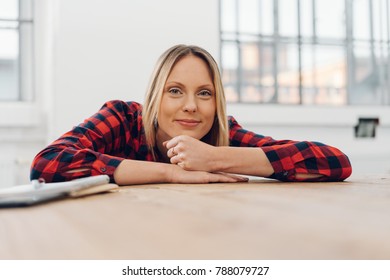 Pretty Relaxed Young Woman Leaning Her Chin On Her Hands On A Table Smiling At The Camera In A Low Angle View