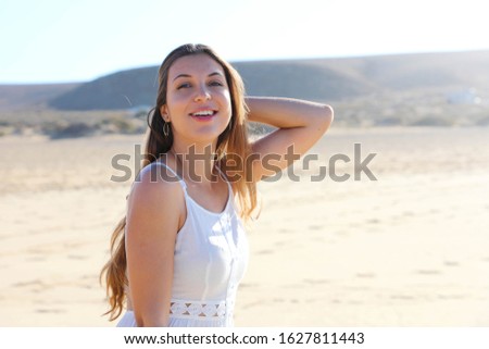 Pretty relaxed young woman smiling at camera walks on the beach