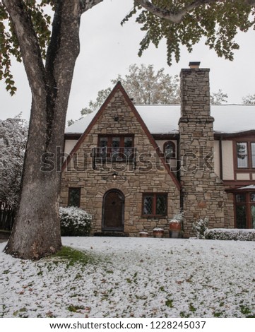 Pretty rock house with arched door and Tudor style leaded glass diamond panel windows during snowfall