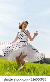 pretty Rockabilly Girl with a petticoat dress is dancing rock & roll on the meadow