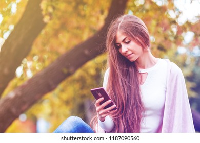 Pretty romantic young woman with a phone in the autumn, toning - Shutterstock ID 1187090560