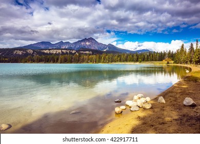 Pretty round lake in the coniferous forest. Canadian Rocky Mountains, Jasper National Park, lake Annette