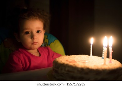 Pretty Sad Little Girl Celebrating Her Happy Birthday With A Cake With Candles. Upset Dissapointed Kid, Baby On The Dark Black Background. Beautiful Cute Lovely Child. Candle Light.