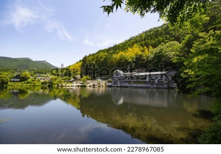 Pretty scenery at Lake Kinrin, Yufuin, Oita, Japan. Japanese text on the house is Lake Kinrin and Rest Place. Yufuin is a popular Onsen resort in Kyushu. small lake with clear water from hot spring