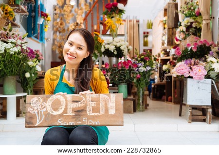 Pretty seller of the shop sitting with Open sign