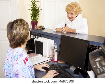 Pretty Senior Lady Checking In At The Doctor's Office Reception Desk.