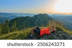 pretty senior woman hiking in warm dawn sunlight and enjoying the spectacular view over the Allgau alps on the Nagelfluh mountain chain near Oberstaufen, Bavaria, Germany