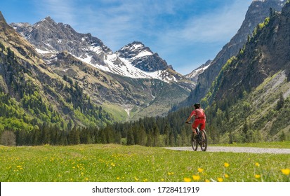 pretty senior woman riding her electric mountain bike the Oy Tal Valley near Oberstdorf, Allgau Alps, Bavaria, Germany