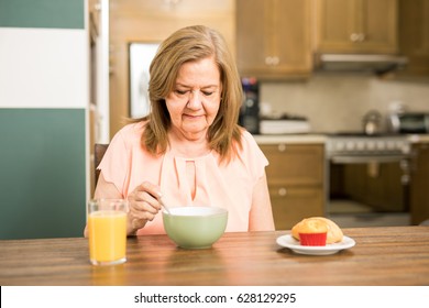 Pretty Senior Woman Sitting In The Kitchen And Without Appetite For Breakfast