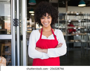 Pretty server in red apron with arms crossed at the bakery - Powered by Shutterstock