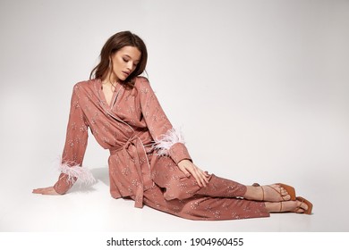 Pretty Sexy Woman Beautiful Face Natural Makeup Brunette Hair Wear Silk Textile Suit Pants And Blouse With Feathers Comfort Casual Home Dress Luxury Lifestyle Pajama Party Glamour Fashion Model.