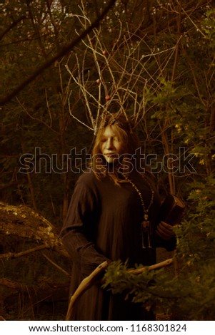 Pretty shaman with book and staff in the forest