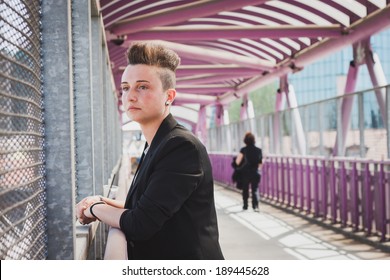 Pretty short hair girl with black jacket posing on a bridge