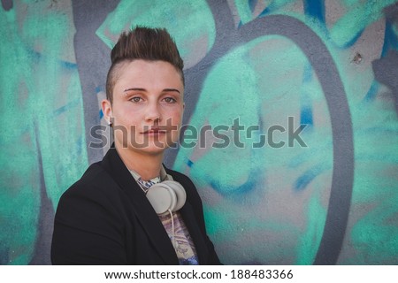Pretty short hair girl with black jacket posing against a wall