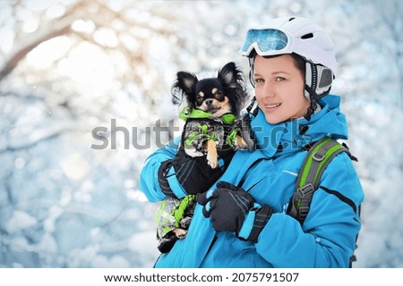 Pretty skier holding chihuahua in hands