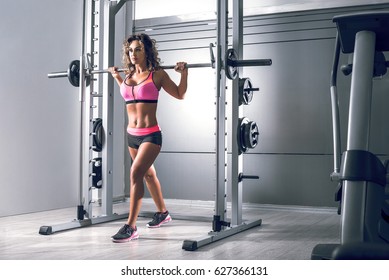 Pretty Slim Fit Female Doing Lunge Exercise At Smith Rack Bar Machine In Modern Fitness Center. Toned Image.