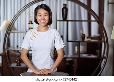 Pretty Smiling Asian Restaurant Hostess Standing At Her Workplace