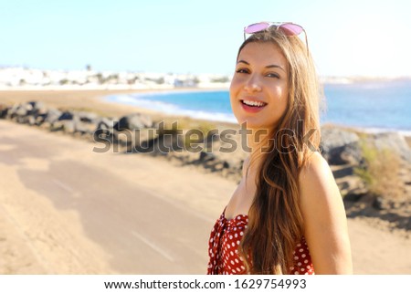 Pretty smiling fashion girl looking at camera outdoor. Happy laughing lovely woman looking happy at camera at ocean sea on summer holidays.