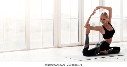 Pretty smiling girl enjoying her morning yoga practice at modern fitness studio, copy studio - Powered by Shutterstock