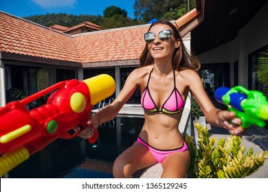 Pretty Smiling Happy Woman Playing With Watergun Toy At Pool On Summer Tropical Vacation On Villa Hotel Having Fun In Bikini Swimsuit, Colorful Style, Party Mood