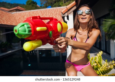 Pretty Smiling Happy Woman Playing With Watergun Toy At Pool On Summer Tropical Vacation On Villa Hotel Having Fun In Bikini Swimsuit, Colorful Style, Party Mood