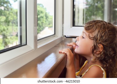 pretty smiling little girl on balcony, look from window