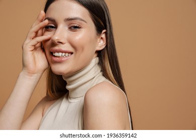 Pretty smiling woman with long straight brown hair posing isolated on beige background