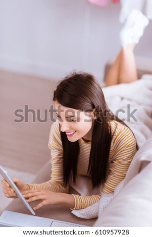 Pretty smiling woman lying on the couch with gadgets and watch in tablet