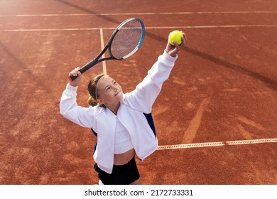 Pretty sports girl with racquet at the tennis court. Tennis player serving. Healthy lifestyle