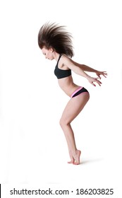 Pretty sporty barefooted woman dancer wearing black top and black pink shorts, dancing, posing, standing on her tiptoes, hair flip up in the air. Over white background