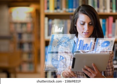 Pretty student working on her futuristic tablet in a library - Powered by Shutterstock