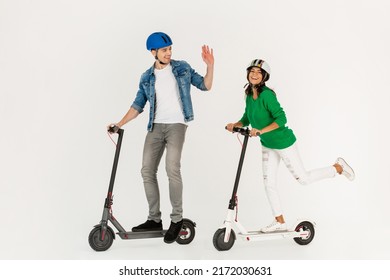 Pretty Stylish Couple Riding On Electic Kick Scooter Isolated On White Studio Background Summer Hipster Style Having Fun Together Smiling Happy, Driving On Speed Wearing Safety Helmets