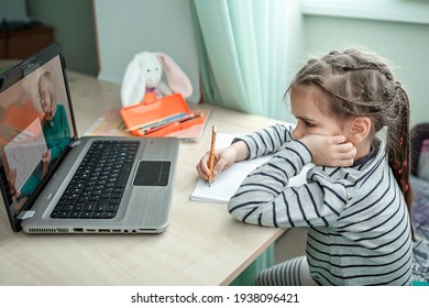 Pretty stylish schoolgirl studying homework math during her online lesson at home, social distance during quarantine, self-isolation, online education concept, home schooler - Shutterstock ID 1938096421