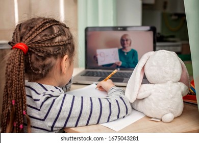 Pretty stylish schoolgirl studying math during her online lesson at home, social distance during quarantine, self-isolation, online education concept - Shutterstock ID 1675043281