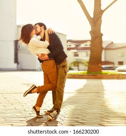 Belo verão ensolarado retrato ao ar livre de jovem casal elegante enquanto se beija na rua.