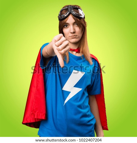 Pretty superhero girl making bad signal on colorful background