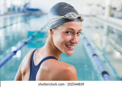 Pretty swimmer by the pool smiling at camera at the leisure center - Powered by Shutterstock