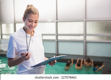 Pretty swimming coach standing poolside at the leisure center - Powered by Shutterstock