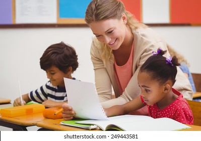 Pretty Teacher Helping Pupil In Classroom At The Elementary School